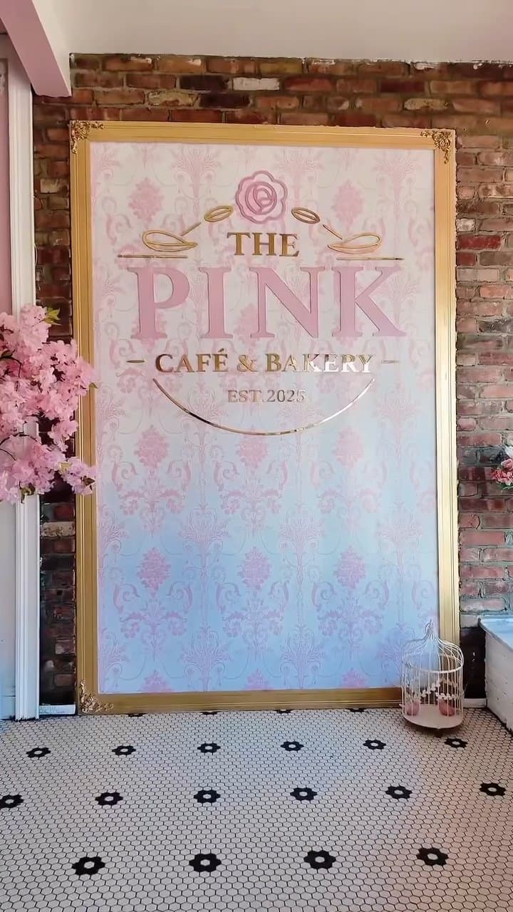 The Pink Cafe and Bakery sign in gold frame against exposed brick